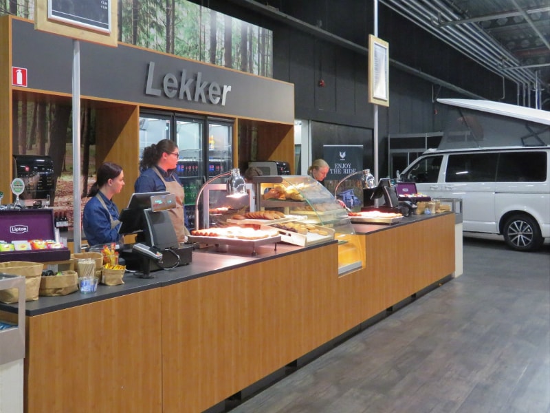 Drei Mitarbeiterinnen an der Theke eines Snackstands auf der Campingmesse in Houten.