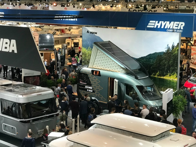 Gut besuchte Campingmesse in Stuttgart mit mehreren Hymer-Campern an einem Stand.