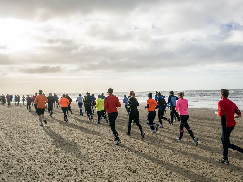 Läufer mit bunten Laufoutfits am Strand von Texel 
