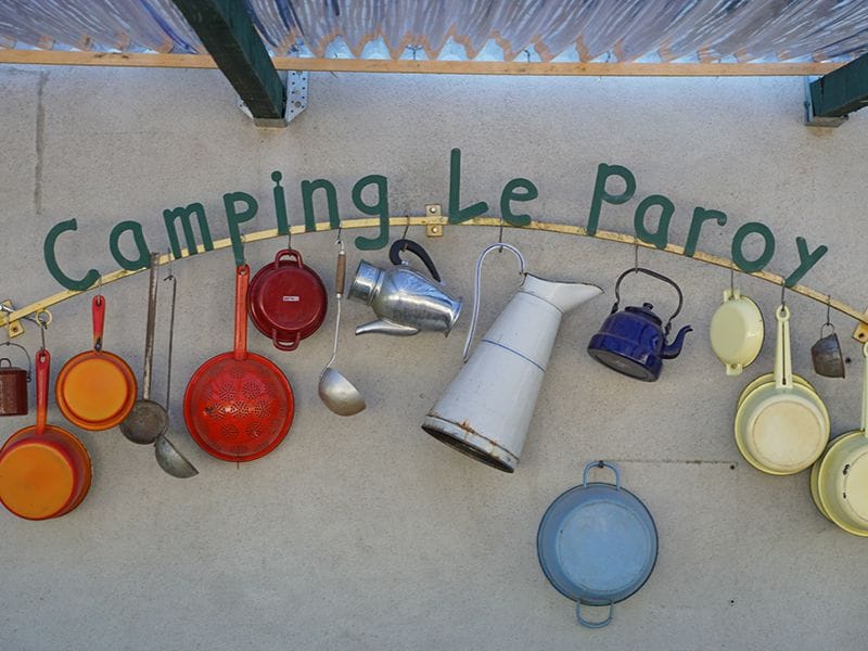 Camping Le Paroy-Namenschild mit dekorativen alten Töpfen und Pfannen