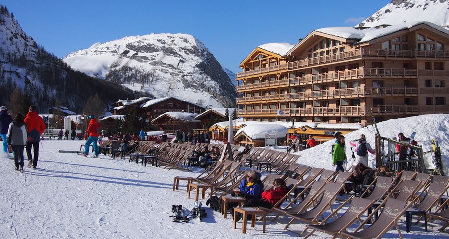 Menschen entspannen in Liegestühlen vor einer Skibar
