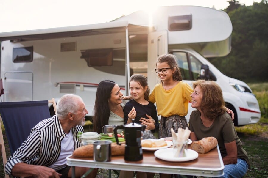 Fröhliche Familie beim Frühstück am Campingtisch