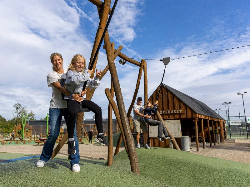 Miriam und Leonie sitzen auf Schaukel und werden von Jens und Petra anschoben.