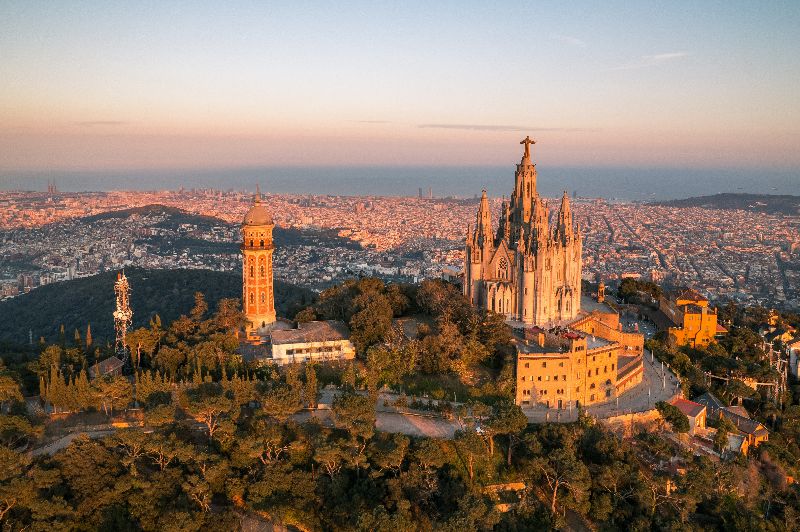 Luftbild der Skyline von Barcelona mit dem Tempel Sagrat Cor bei Sonnenuntergang