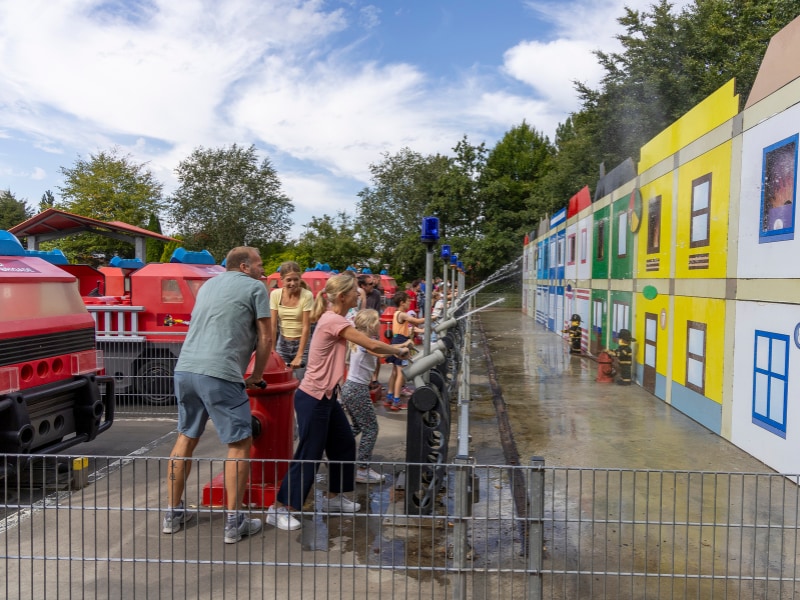 Leonie und Jens pumpen Wasser, Petra und Miriam richten den Feuerlöscher auf das Feuer.