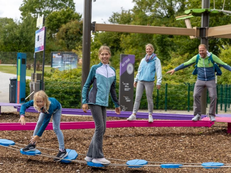 Miriam und Leonie balancieren auf einem Hindernis im Vordergrund, Petra und Jans auf einem anderen im Hintergrund