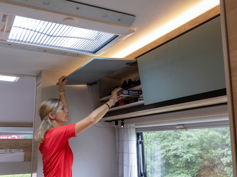 Petra holt ein Puzzel aus der Schrank über dem Esstisch