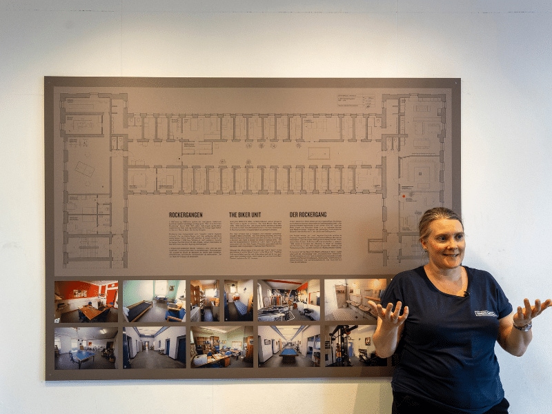 Guide Anne steht vor Grundriss des Rockerabteils.