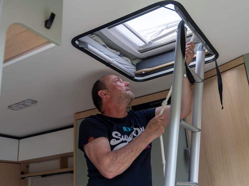 Frank steht auf der Leiter um das Aufstelldach aufzubauen