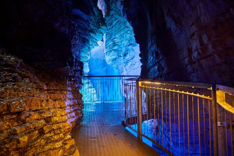 Beleuchtete Höhle und Steg im Inneren des Varone Wasserfalls bei Riva del Garda.