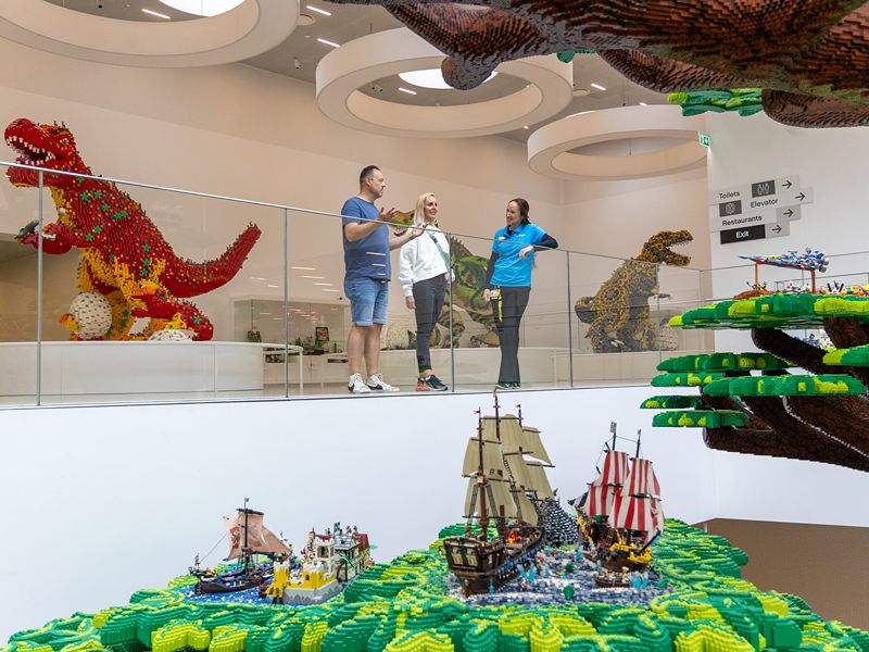 Ricarda und Lars stehen mi ihrem Guide vor LEGO® Bauten und bestaunen den Baum der Kreativität