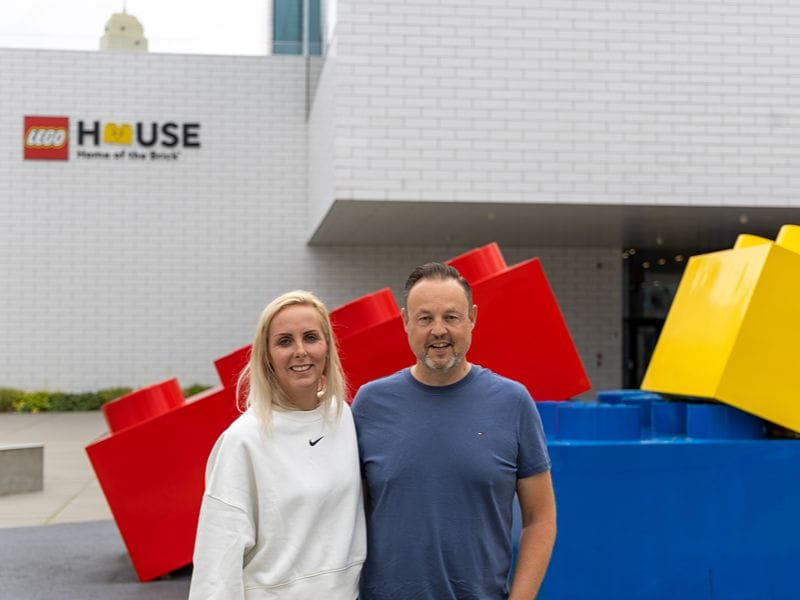 Ricarda und Lars stehen vor großen bunten LEGO® Steinen vor dem LEGO® House