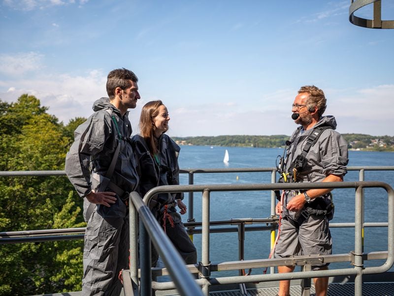 Maja und Felix stehen auf der Brücke und erfahren von Guide Jakob interessantes über die Umgebung