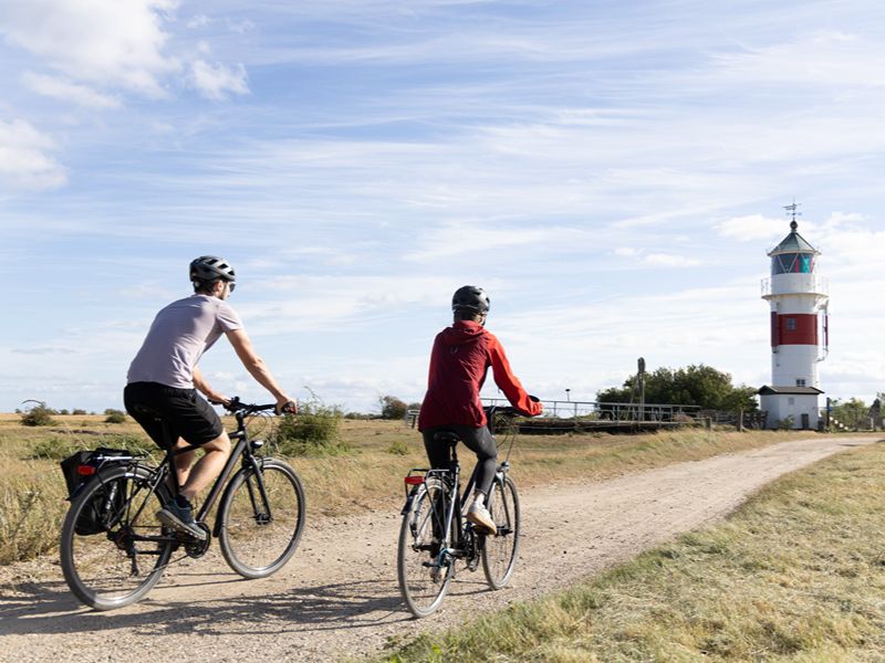 Maja und Felix fahren mit dem Fahrrad in Richtung Leuchtturm