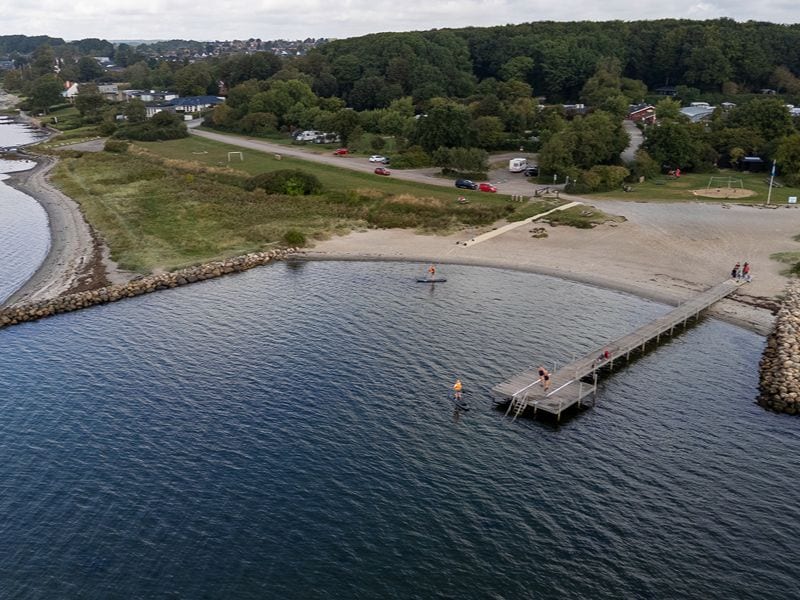 Ansicht von oben auf den Steg am Horsens CIty Camping, mit Menschen auf dem Steg und zwei Personen auf SUP-Brettern.