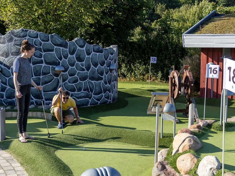 Maja und Felix beim Minigolfspielen, Felix schaut kritisch wohin sein Ball rollt.