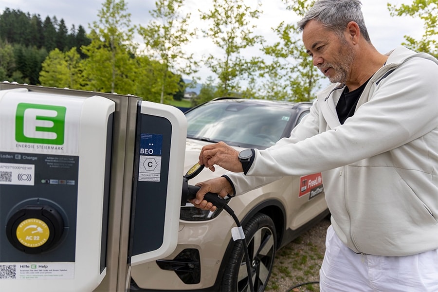 Mann schließt Auto an eine Ladesäule an