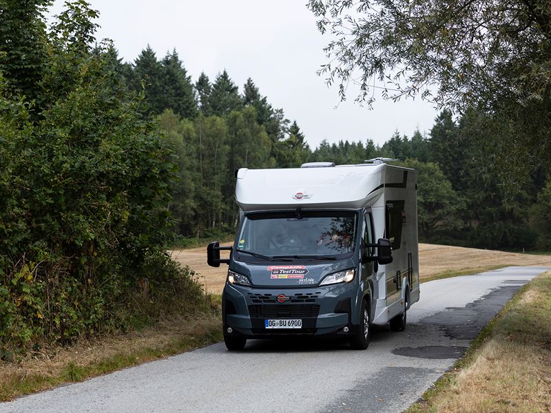 Außenansicht des Campers Bürstner Lyseo Time SkyLine EDITION T 690 G auf einer Landstraße mit Bäumen und Feldern