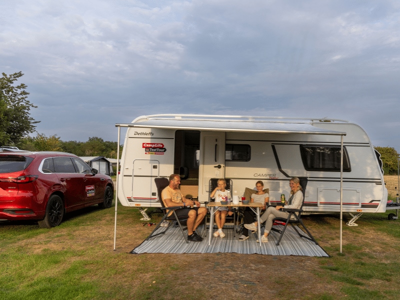 Die Rienhoffs sitzen unter der Markise am Tisch vor ihrem Caravan