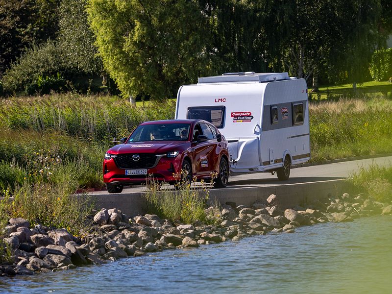Mazda CX-60 mit LMC Style 400 F fährt entlang eines Fjords mit viel grün im Hintergrund