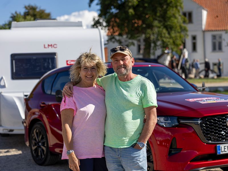 Herta und Frank stehen vor ihrem Gespann aus rotem Mazda und LMC Caravan