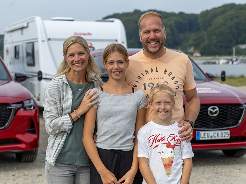Petra, Jens, Miriam und Leonie Rienhoff stehen lachend vor ihrem Caravan-Gespann