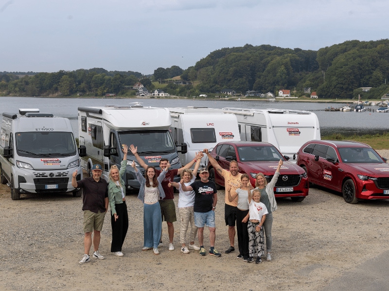 Gruppenbild aller Teams inklusive Fahrzeuge vor dem Fjord