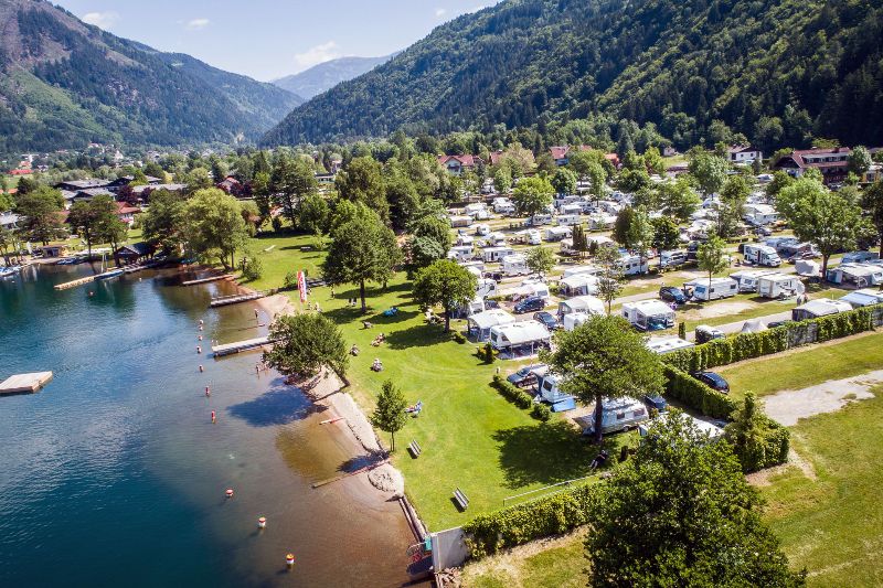 Campingplatz Brunner am See am Millstätter See mit Strand, Stellplätzen und Bergen im Hintergrund