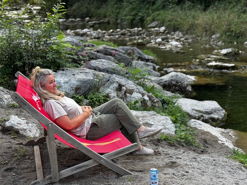 Laima sitzt in einem Liegestuhl am Fluss